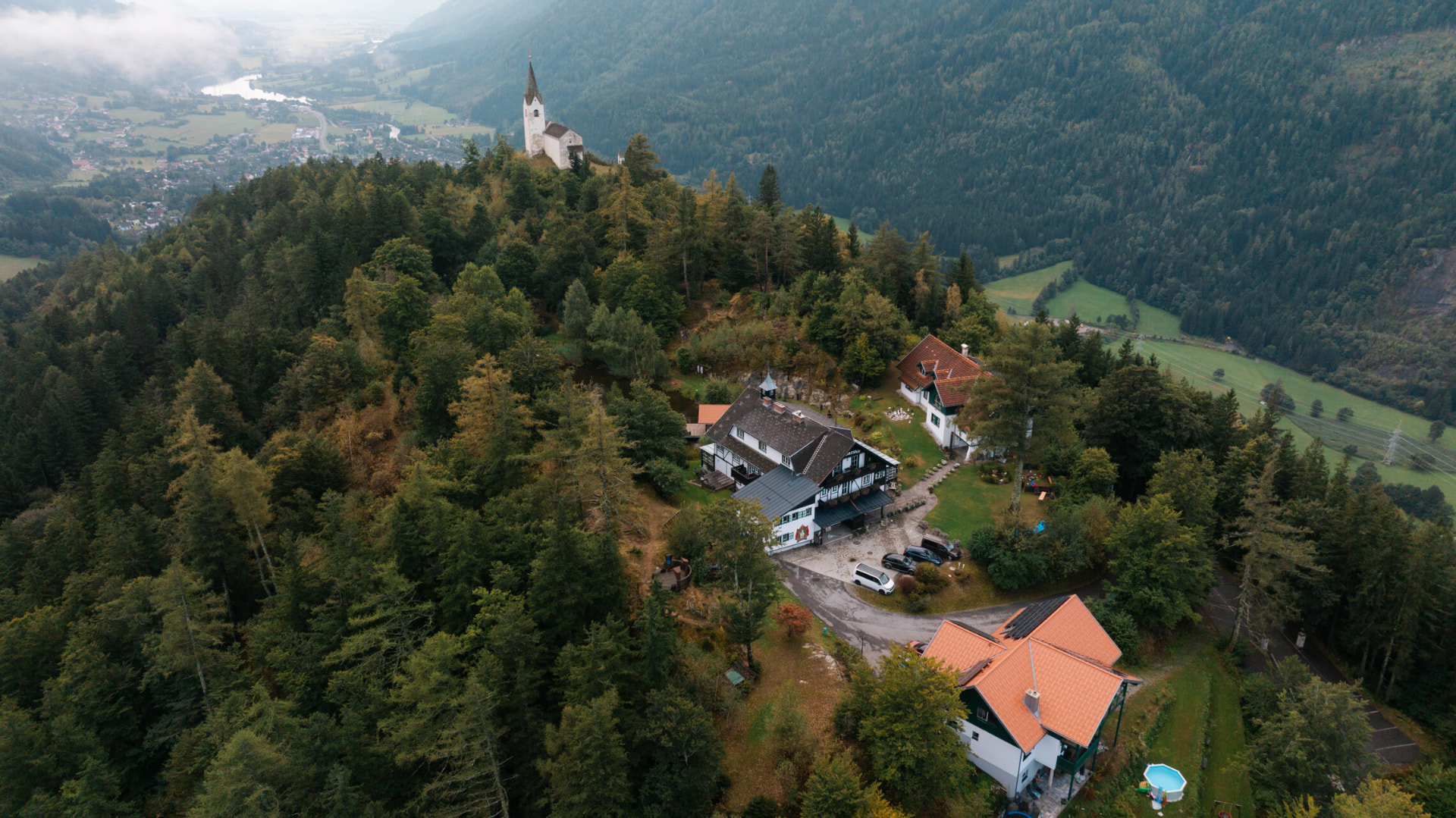 Luftaufnahme des Herkuleshofs im Wald, darüber die Kirche St. Georg