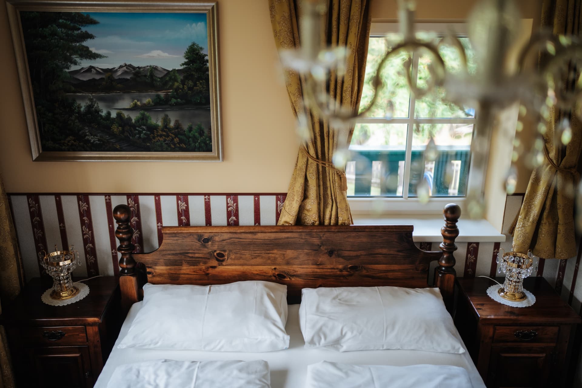 Doppelzimmer mit Holzbett und Blick durchs Fenster ins Grüne